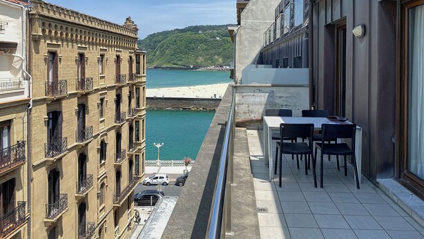 A balcony with a view of a coastal area, featuring a dining table and chairs. - Boulevard Terrace by FeelFree Rentals (Donostia)