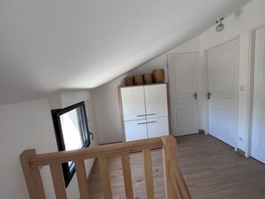 Cozy loft-style room with a wooden floor, white wardrobe, and wicker baskets.
