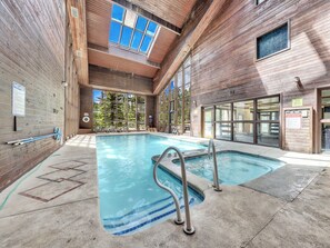 Relax by the pool with a clear view of the water, pool ladders, and a geometric tile floor.