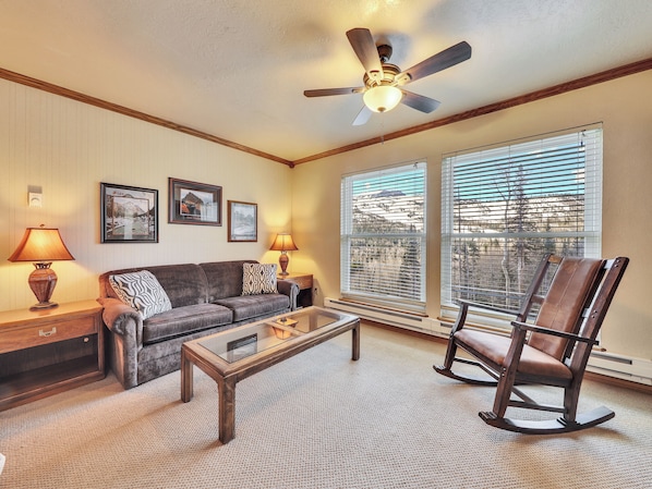 Relax in this inviting living room with a sofa set, wooden coffee table, and rocking chair.