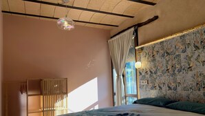 Een slaapkamer met een bed, een hanglamp, een raam met gordijnen en een muur met een vogelprint.