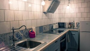 Een keuken met een spoelbak, een magnetron, een broodrooster en een koelkast.