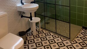 Een badkamer met een wit toilet, een wastafel en een douche met glazen wand.
