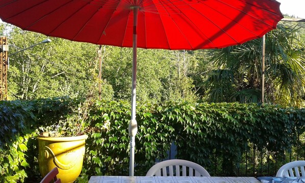An outdoor seating area with a red umbrella, a yellow planter, and white chairs. - Mas Cévenol à Proximité du Village et de la Rivière (Lasalle)