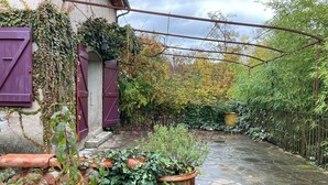A stone pathway leading to a rustic building with ivy-covered walls and a large planter filled with greenery. - Mas Cévenol à Proximité du Village et de la Rivière (Lasalle)