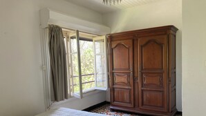 A bedroom with a bed, a wardrobe, and a window with curtains. - Mas Cévenol à Proximité du Village et de la Rivière (Lasalle)