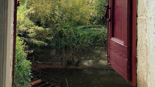 A rustic stone building surrounded by dense greenery and a small water body. - Mas Cévenol à Proximité du Village et de la Rivière (Lasalle)