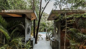 En gång leder fram till en pool som omges av frodig grönska och modern arkitektur.