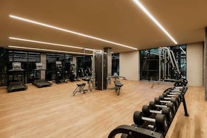 Et fitnesscenter med løbebånd, styrkemaskiner og håndvægte.