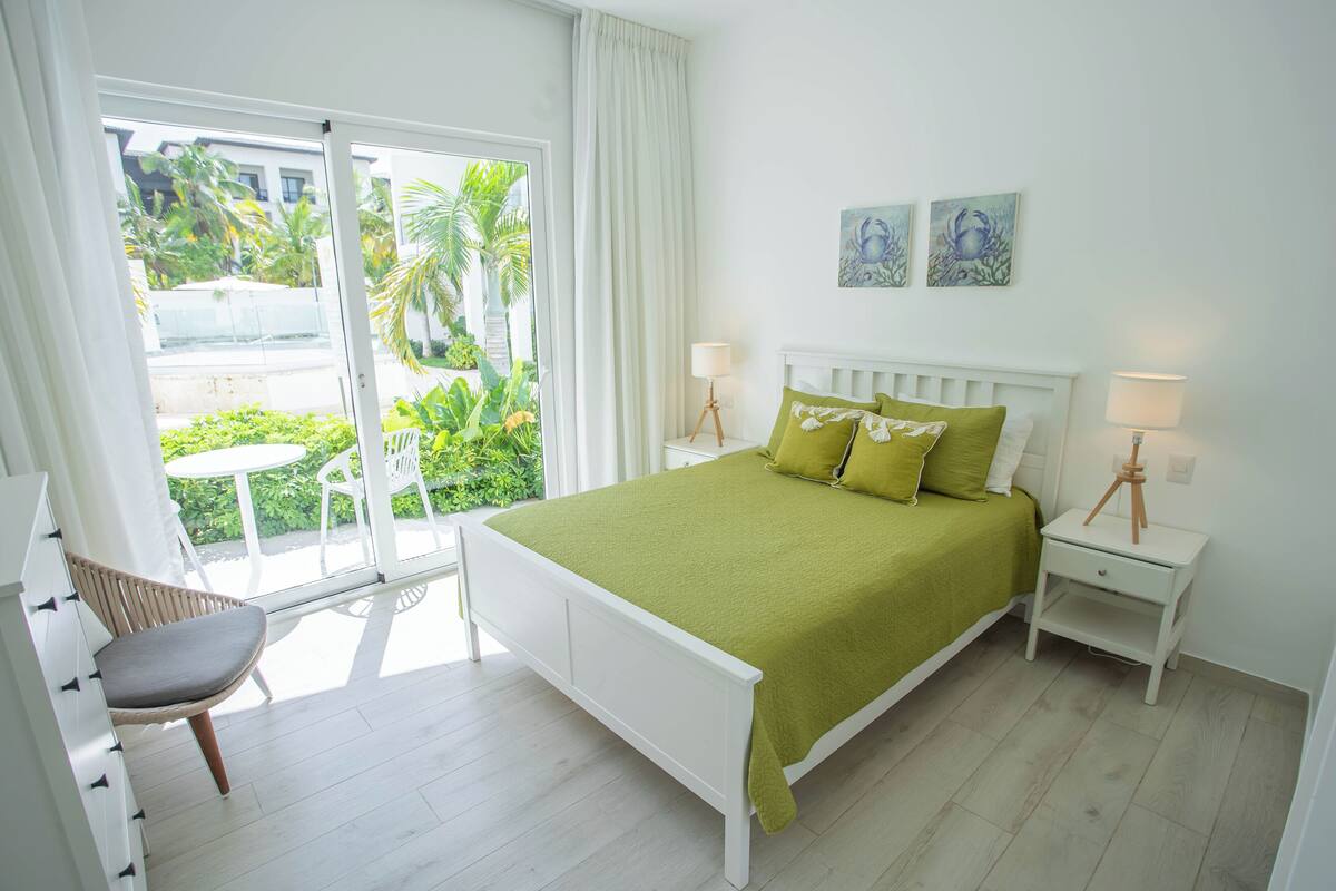 Une chambre avec un lit, une chaise, une table de chevet et une vue sur la verdure.