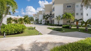 A resort with a central pathway, palm trees, and modern buildings with balconies. - Xeliter Playa Coral Bavaro (Punta Cana)
