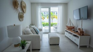 A modern living room with a sofa, a coffee table, a TV, and a wooden sideboard. - Xeliter Playa Coral Bavaro (Punta Cana)