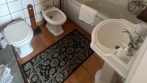 A small bathroom with a toilet, bidet, bathtub, and sink.