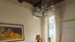 A hotel room with a bed, a desk, a lamp, a painting, and a chandelier.