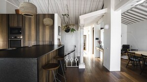 A modern kitchen with a central island, bar stools, hanging plants, and a dining area with a table and chairs. - Casa Porto with Sea View (Málaga)