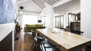 A spacious dining area with a long wooden table and black chairs, a green sofa, and a large window providing natural light. - Casa Porto with Sea View (Málaga)