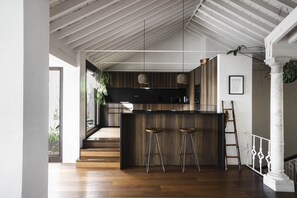 A modern kitchen with a wooden island, bar stools, and pendant lights. - Casa Porto with Sea View (Málaga)