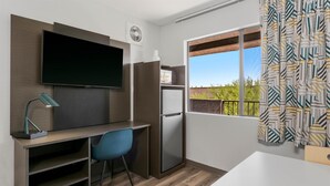 A compact kitchenette with a built-in microwave, refrigerator, and a flat-screen TV mounted on the wall. - Studio 6 Tempe, AZ – Elliot Road (Tempe)