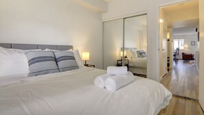 A hotel room with a large bed, a wardrobe, and a mirror. - Stylish DT Views at Stampede w/ Free Parking, AC (Calgary)