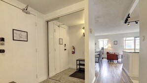 A hallway with a door leading to a dining area, a fire extinguisher, and a framed architectural drawing on the wall. - Stylish DT Views at Stampede w/ Free Parking, AC (Calgary)