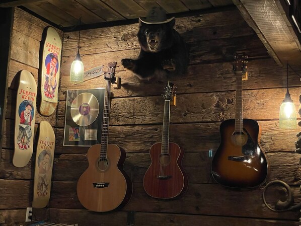 Un mur en bois orné de guitares, d’un CD et d’une planche de skate.