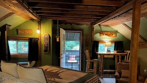 A cozy room with a bed, a desk, and a chair. There's a window with a view of greenery outside. - Grunberg Haus Inn & Cabins (Waterbury)