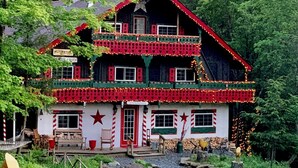 A two-story building with a red and white facade, multiple windows, and a balcony. - Grunberg Haus Inn & Cabins (Waterbury)