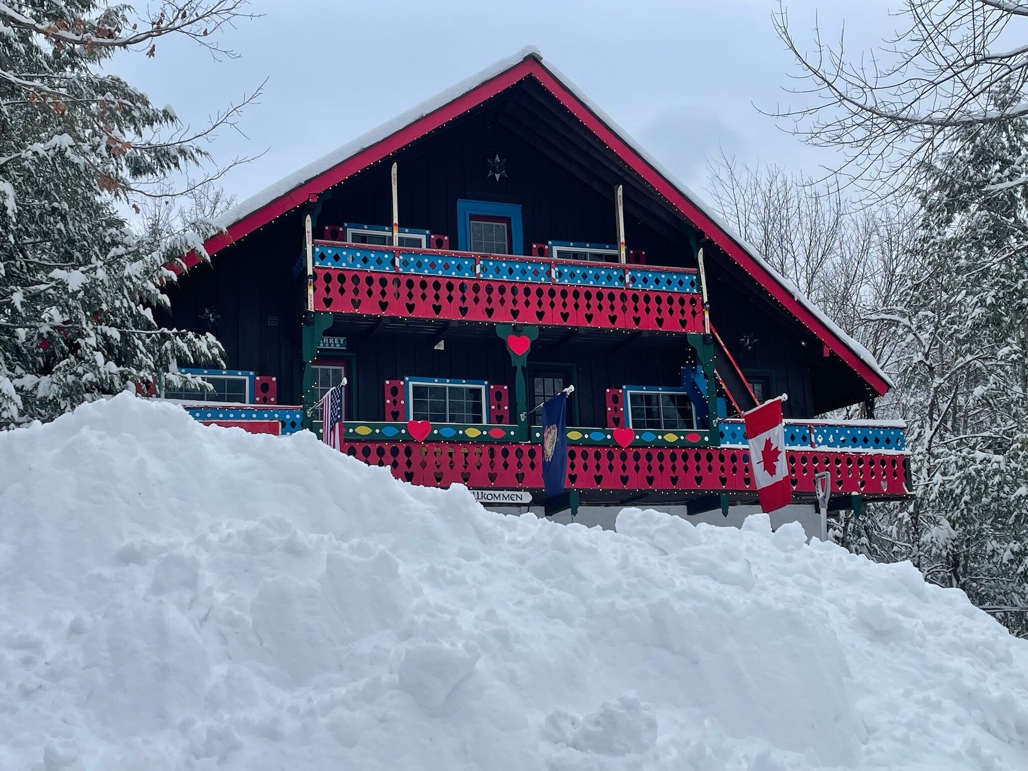 A two-story building with a red roof and a balcony, surrounded by snow.