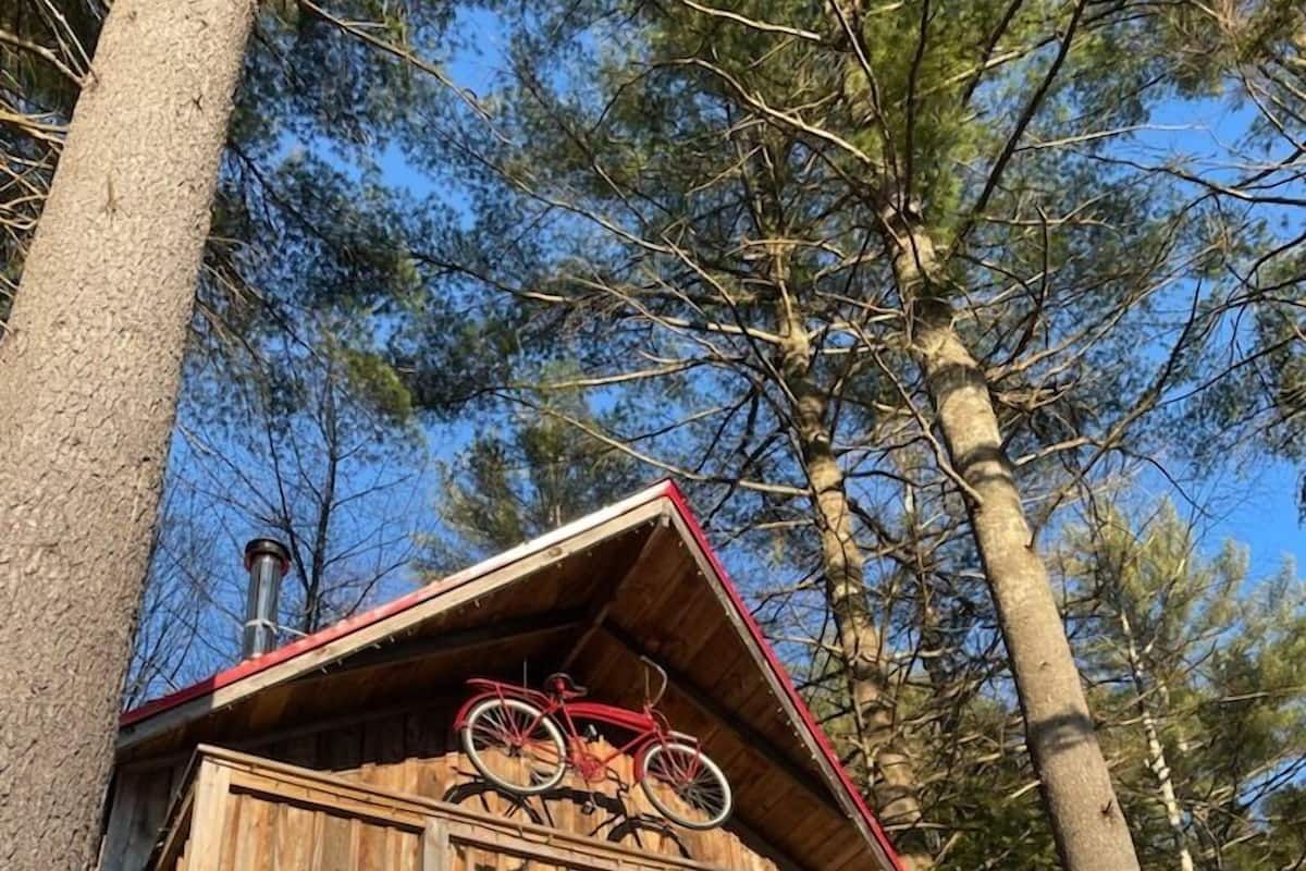 Una cabaña de madera con balcón, una bicicleta y una chimenea.