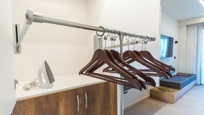 A modern hotel room with a wooden wardrobe, a drying rack, and a flat-screen TV. - Aura Luxury Suites - Olympiada Cozy Getaways (Aristotelis)