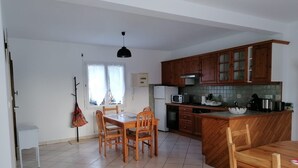 Cocina compacta con muebles de madera, una mesa de comedor y sillas.