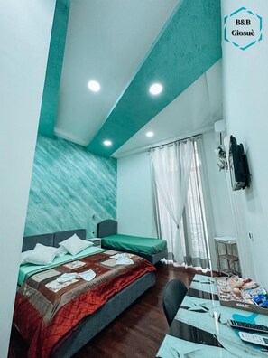 Habitación de hotel con cama, escritorio con silla, televisor montado en la pared y ventana con cortinas.