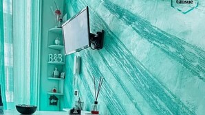 A teal-themed reception desk with a mounted screen, a shelf with decorative items, and a wall with a textured pattern. - B&B Giosuè (Naples)