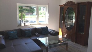 Una sala de estar con un sofá modular, una mesa de centro de vidrio y un aparador de madera con espejo.