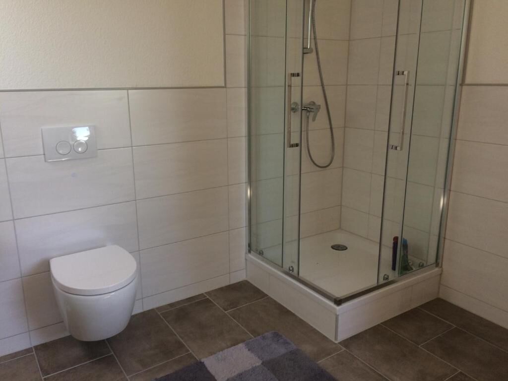 Un bagno con cabina doccia in vetro, un WC e un pannello di controllo.