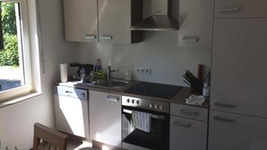 Cocina compacta con lavavajillas, estufa, pileta y ventana que proporciona luz natural.