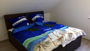 Una cama con colcha y almohadas a rayas azules y blancas con motivos playeros.