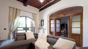A living room with a sectional sofa, a wooden door with glass panels, and a window with curtains.