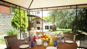 A round wooden table set for breakfast with plates, cups, and a fruit bowl.