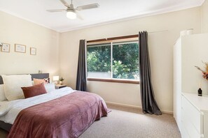 A bedroom with a bed, a nightstand, a dresser, a window with curtains, and a ceiling fan. - The Peach Tree 2 Bed Home (Elizabeth Vale)