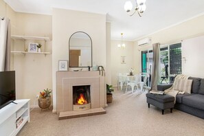 A living room with a fireplace, a sofa, a TV, and a dining area with chairs and a table.