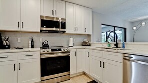 Una cucina moderna con mobili bianchi, elettrodomestici in acciaio inossidabile, un forno a microonde, un tostapane e una lavastoviglie.