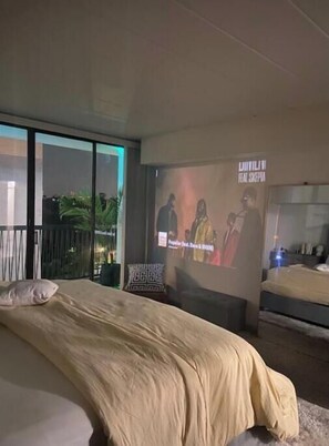 Relax in a spacious room with a large bed and sliding door leading to an outdoor area.