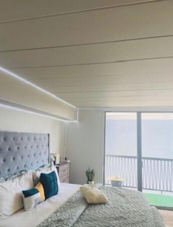 Relax in a serene space with a large bed, a bedside table, and a potted plant, offering scenic views.