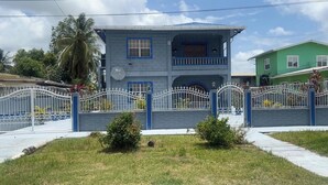A two-story house with a blue exterior, a balcony, and a white fence.