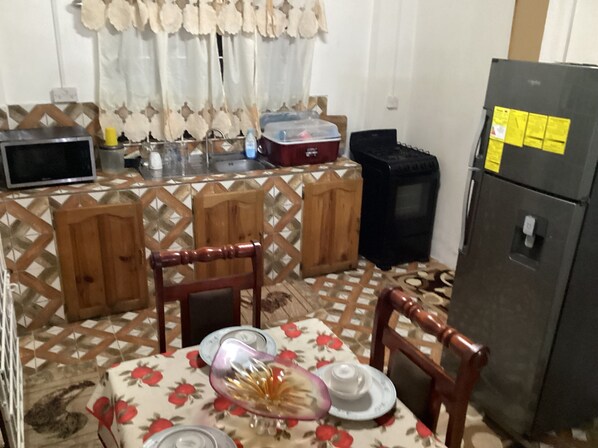 A kitchen with a dining table set for two, a refrigerator, and a microwave.