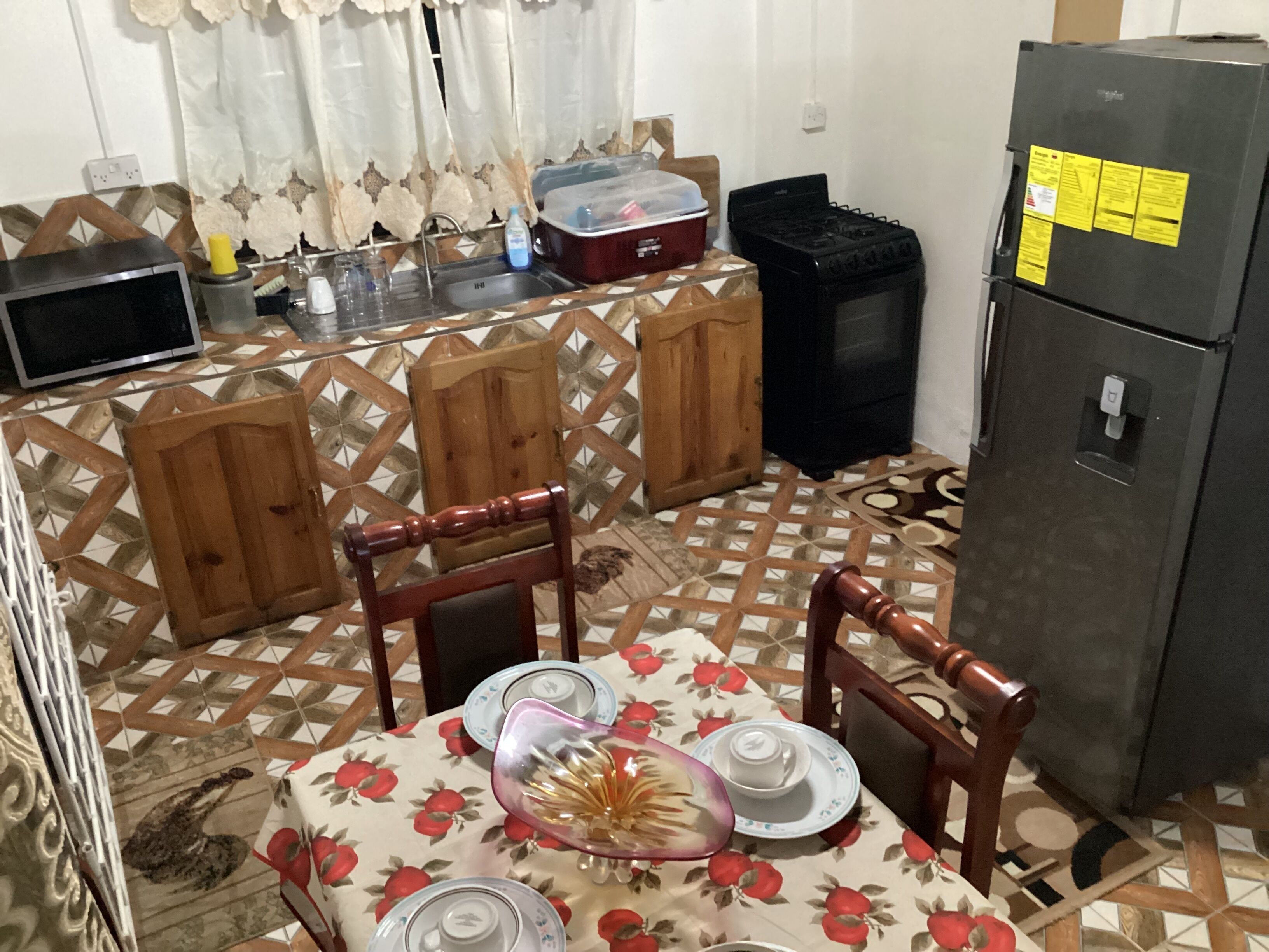 A compact kitchen with a dining table set for two, a refrigerator, and a microwave.