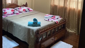 A bedroom with two beds, a ceiling fan, and curtains.