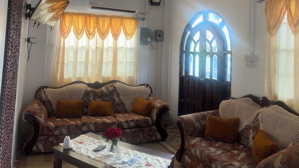 A living room with patterned sofas, a ceiling fan, and a decorative ceiling.