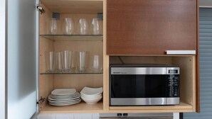 Une cuisine équipée d’un four à micro-ondes, de verres et d’assiettes empilées.